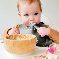 baby enjoying holle oat cereal in high chair