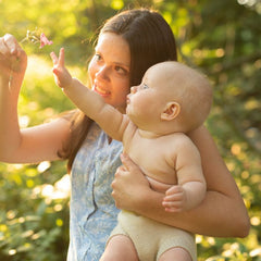 mom and baby admiring a flower outside