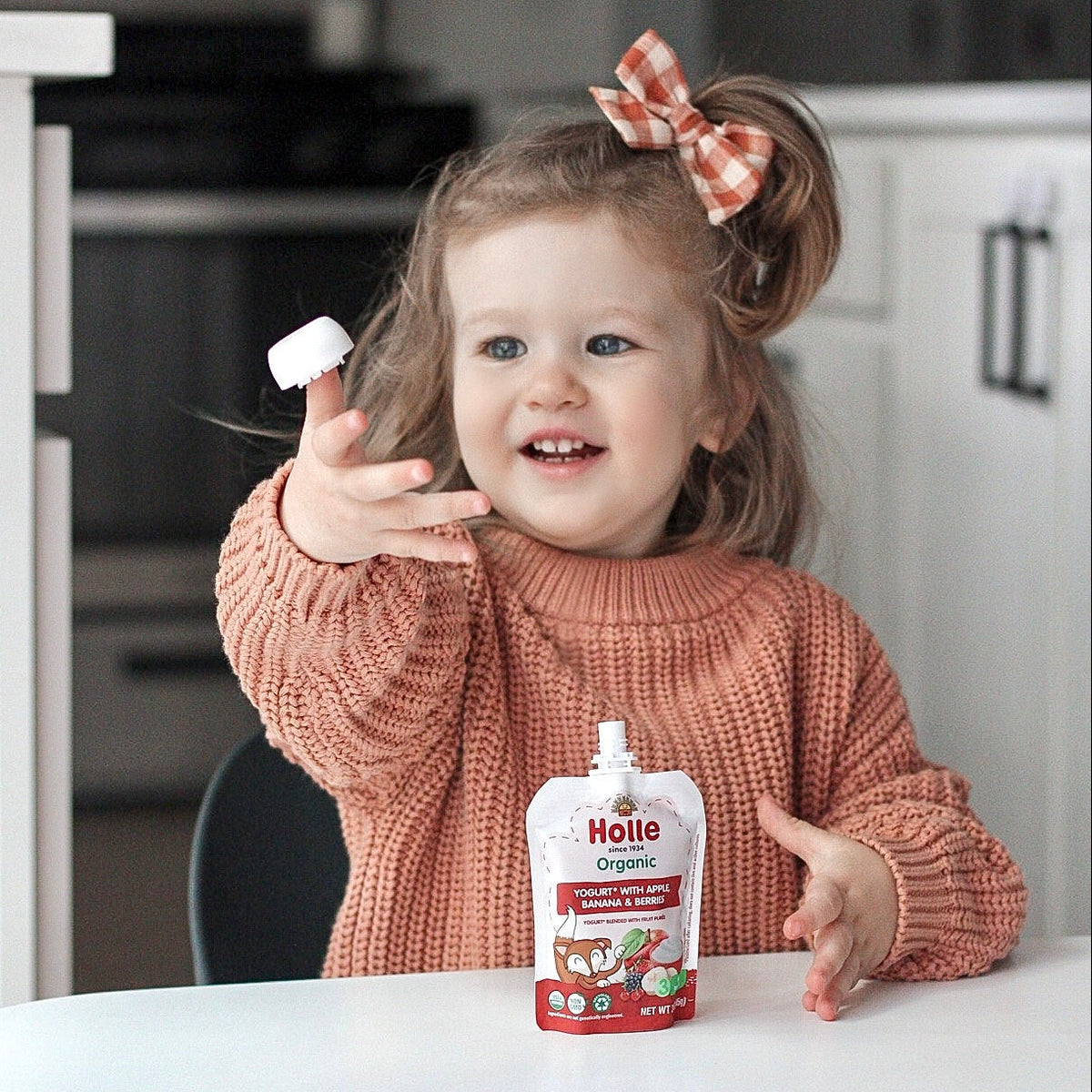kid enjoying yogurt pouch at the kitchen table